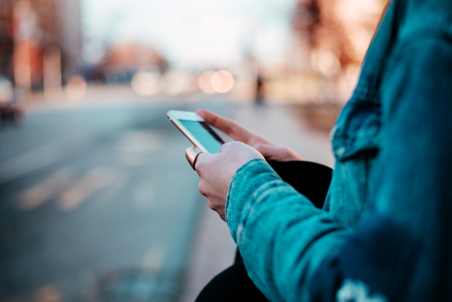 person using a cell phone on the side of the street