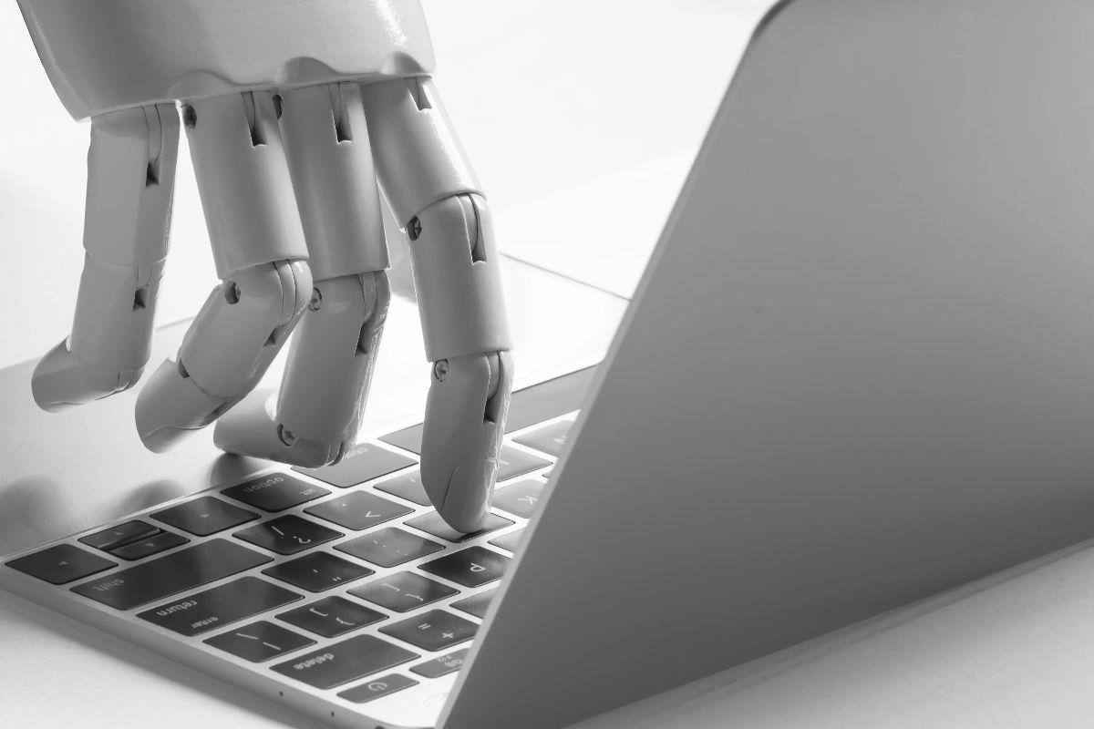 robot hand typing on laptop