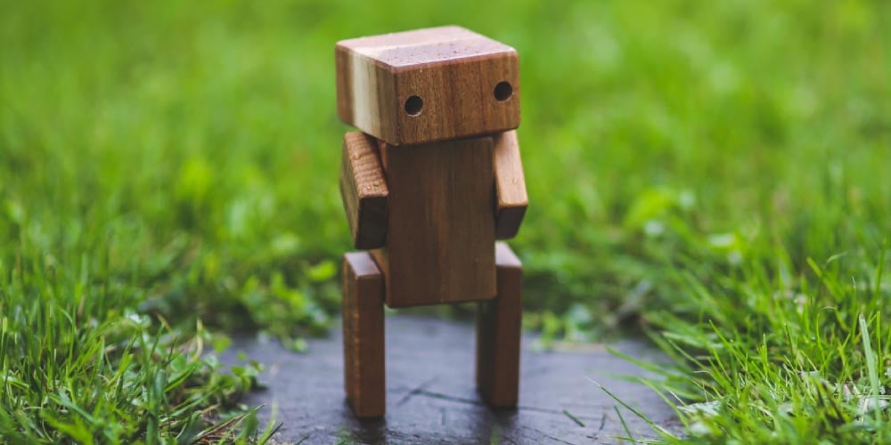 Wooden Robot committing standing on a stone in grass
