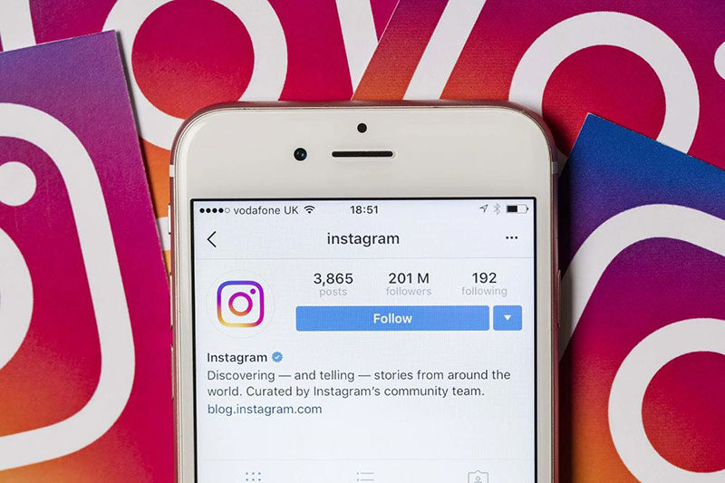 Instagram account pulled up on cell phone with logo in background