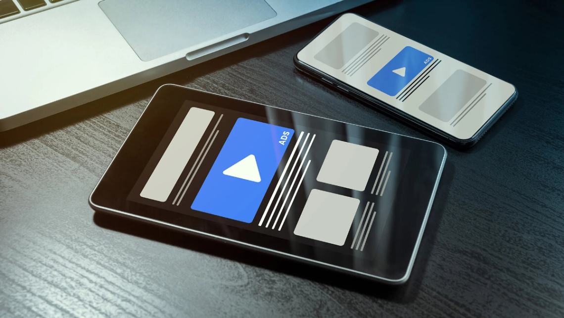 Tablet and phone laying on laptop with programmatic native ads on them