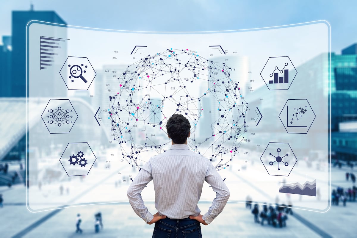 back of businessman looking at analytics superimposed on a clear window