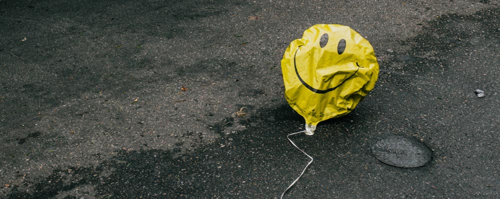 deflated smiley face balloon in street