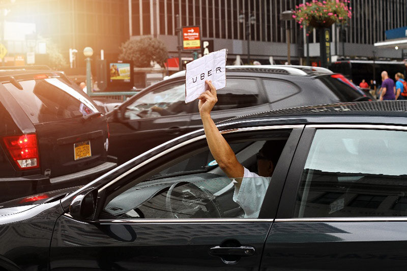 car driver holding uber sign out the window in new york city